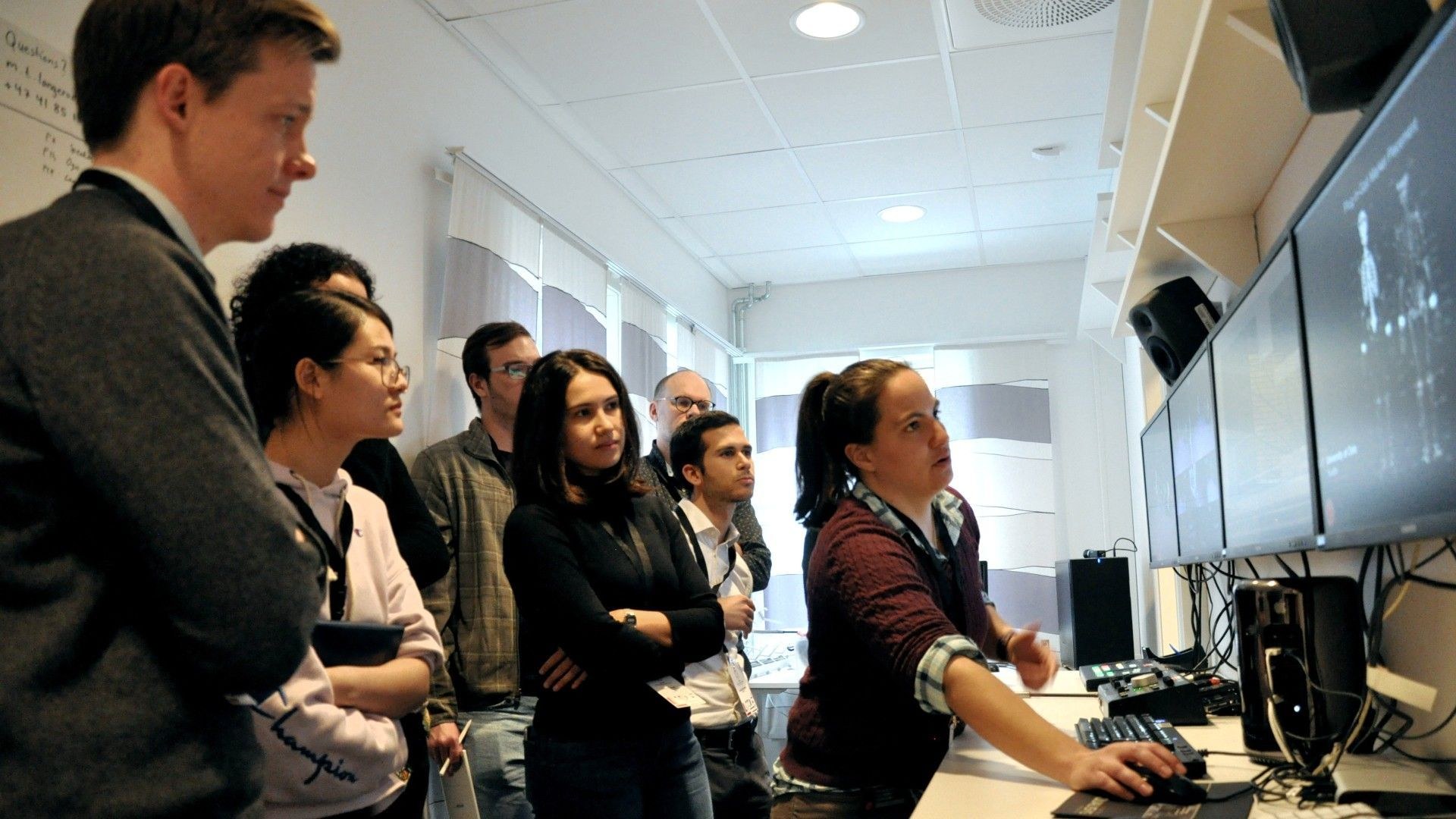 Participants at a winter school gathered around the control room screens