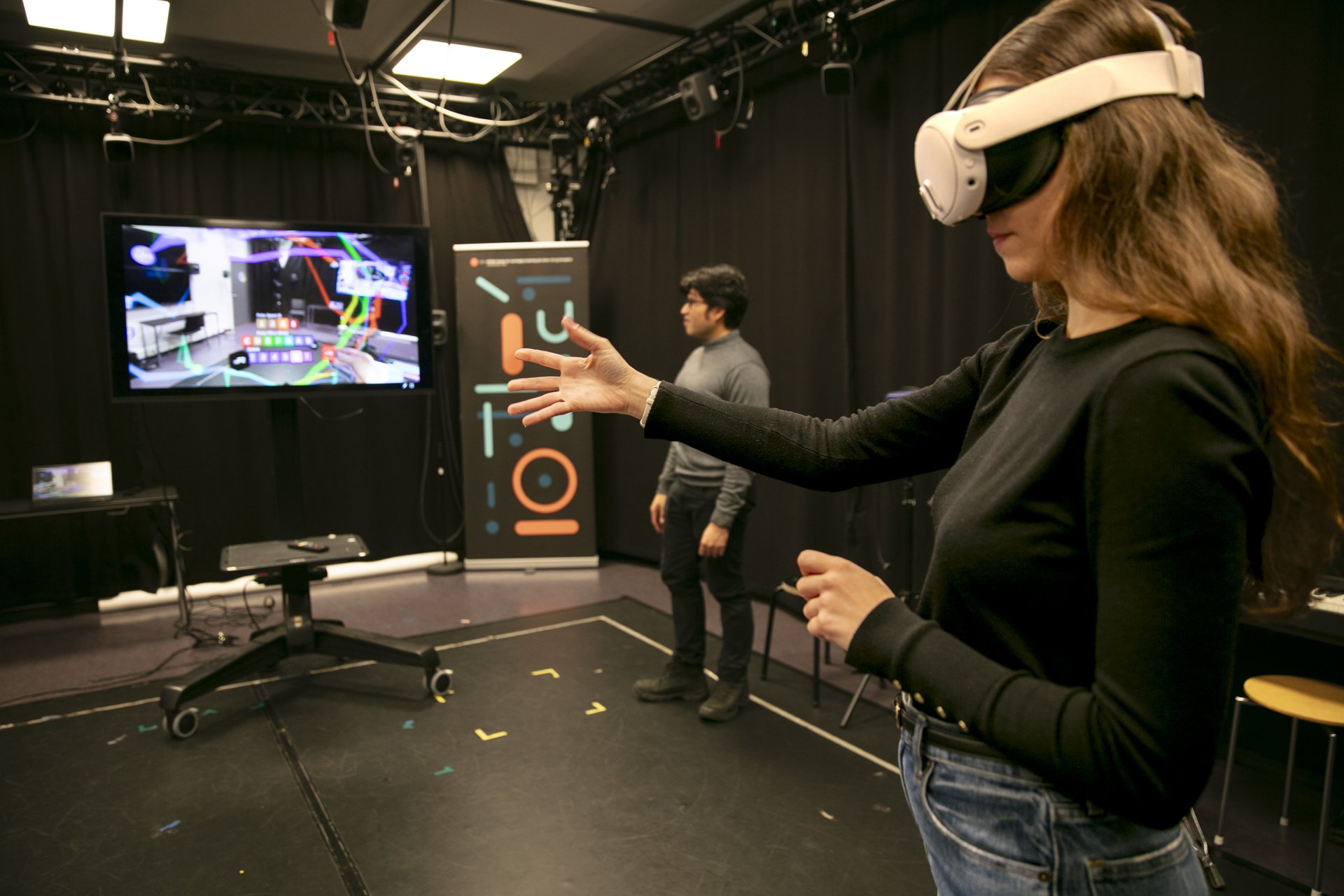 A participant with a VR headset making music with hand gestures in the motion capture lab